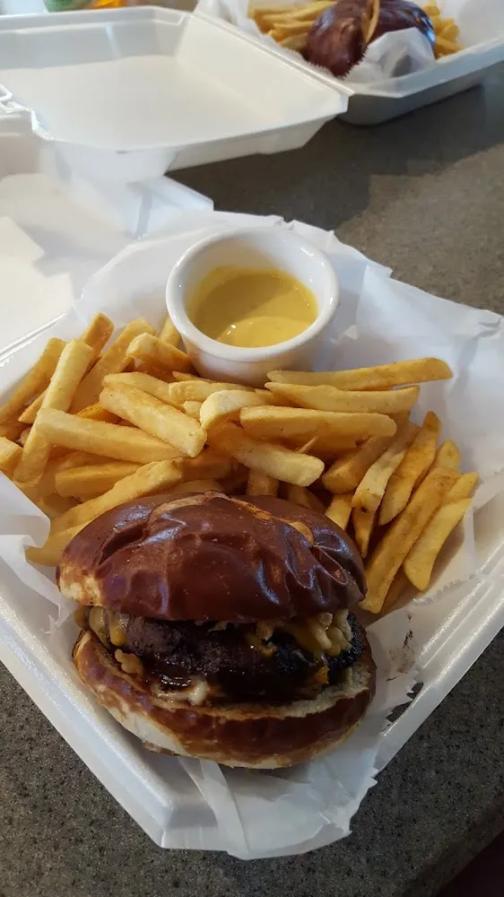 Pretzel Bun Burger with Boursin Cheese Onion Straws BBQ Sauce and Fries Take-Out